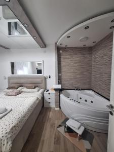 ein Schlafzimmer mit einem Bett und einer Badewanne sowie einem Bett und einem Bettrock in der Unterkunft JACUZZI LUX SANJA in Subotica