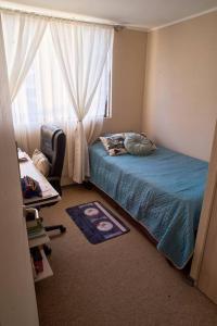1 dormitorio con cama, ventana y silla en Departamento amoblado en arriendo, en Arica