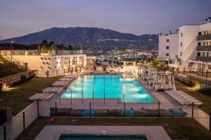 a swimming pool with lounge chairs and a building at Hacienda el Sueno in Fuengirola