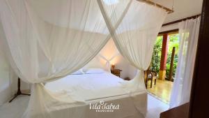 1 dormitorio con cama con dosel y cortinas blancas en Pousada Vila Sabiá Trancoso, en Trancoso