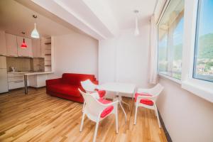 salon ze stołem, krzesłami i czerwoną kanapą w obiekcie Apartment DV Magnolia w mieście Tivat