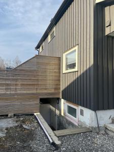 Koselig kjellerleilighet sentralt på Orkanger في أوركانغير: منزل بحائط خشبي بجانب مبنى