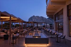 a restaurant with tables and chairs with a mountain in the background at Atlantica Imperial Resort - Adults Only in Kolimbia