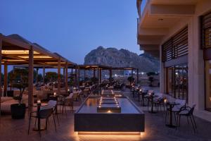 a restaurant with tables and chairs with a mountain in the background at Atlantica Imperial Resort - Adults Only in Kolymbia