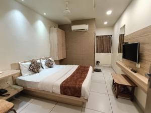 a hotel room with a bed and a television at Hotel Kinara in Ahmedabad