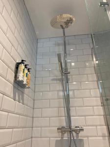 a shower in a bathroom with white tiles at Beautiful Retro Flat above Pub. in Shepton Mallet