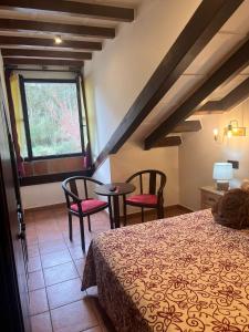 een slaapkamer met een bed en 2 stoelen en een raam bij Hotel El Bricial in Soto de Cangas