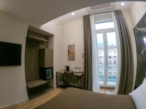 1 dormitorio con cama, escritorio y ventana en Municipio Luxury Suite en Nápoles