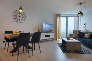uma sala de estar com um sofá e uma mesa com cadeiras em Apartament Premium Sea View PINEA 712 em Pobierowo