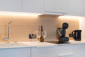 a kitchen with two wine glasses and a sink at Apartament Premium Sea View PINEA 712 in Pobierowo