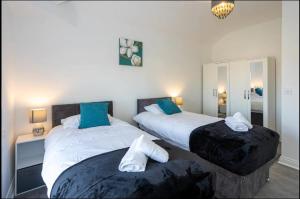 a bedroom with two beds with blue pillows at 2 Bed Flat Prenton - Apartment 3 in Birkenhead