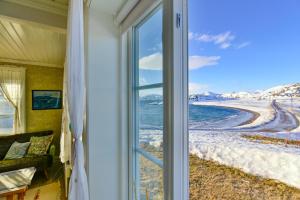 a window with a view of the beach at Kongsfjord Arctic Lodge in Kongsfjord
