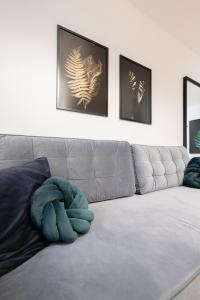 een woonkamer met een grijze bank met twee foto's bij Glow Apartments, Apartament Luna Śródmieście in Gdańsk