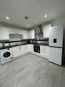cocina con armarios blancos, lavadora y secadora en Fully furnished 1 Bedroom flat en Londres