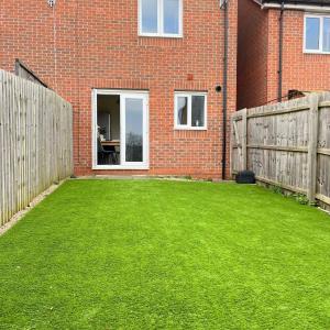 a backyard with a green lawn in front of a brick building at 2 bed house near Ricoh Arena, 2xparking, wifi in Longford