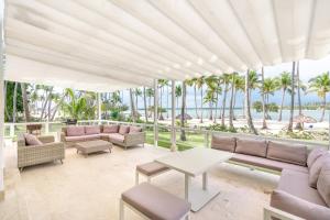 une terrasse avec des canapés, une table et des palmiers dans l'établissement Beach front and beach access at Nueva Romana, à Juan Dolio