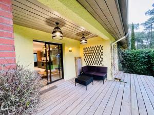 a porch with a bench on a wooden deck at Villa Patio à 800 m de la plage in Seignosse