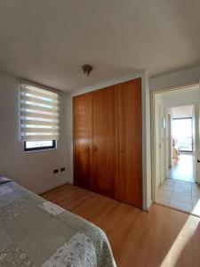 a bedroom with a bed and a wooden closet at Departamento El Encanto - Reñaca in Viña del Mar