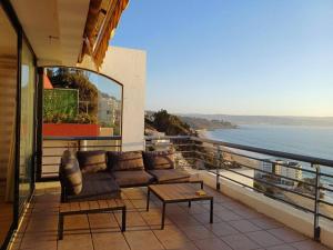 a couch on a balcony with a view of the ocean at Departamento El Encanto - Reñaca in Viña del Mar