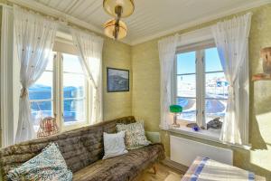 a living room with a couch and two windows at Kongsfjord Arctic Lodge in Kongsfjord