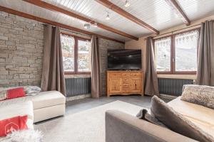 a living room with a couch and a television at Gîte Le Cembro 6 personnes in Termignon