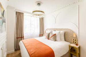 a bedroom with a white bed with an orange and white blanket at Luxury 3 Bedroom & 3 Bathroom Apartment - Marais in Paris