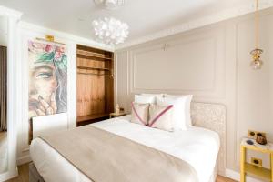 a bedroom with a white bed with a painting on the wall at Luxury 3 Bedroom & 3 Bathroom Apartment - Marais in Paris