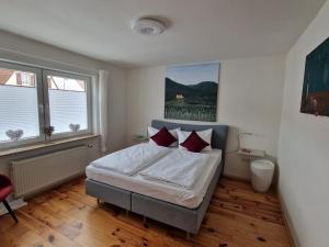 1 dormitorio con 1 cama con sábanas blancas y almohadas rojas en BigFish, en Großfischlingen
