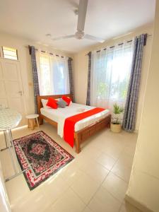 a bedroom with a bed with red sheets and windows at MASKANI COSY APARTMENT - Nyali, Mombasa. in Mombasa