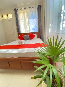 a bedroom with a bed with red pillows and a plant at MASKANI COSY APARTMENT - Nyali, Mombasa. in Mombasa +8 photos