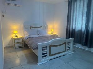 um quarto com uma cama branca e duas mesas de cabeceira em Villa bord de mer louis em Libreville