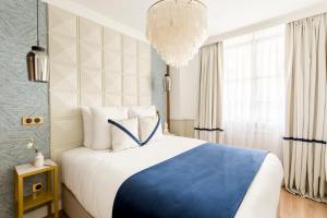Un dormitorio con una cama azul y blanca y una lámpara de araña. en Luxury 2 Bedroom & 2 Bathroom Suite - Marais en París