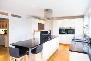 a kitchen with white cabinets and black countertops at Seaflowers in Kingsbridge