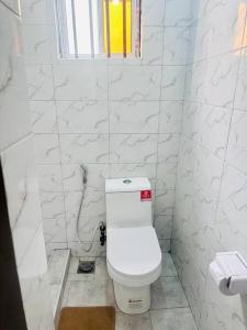 biała łazienka z toaletą i oknem w obiekcie kaya homes w mieście Dar es Salaam