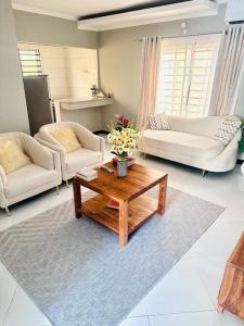 Sala de estar con 2 sofás y mesa de centro en kaya homes, en Dar es Salaam