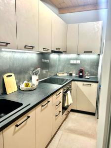 a kitchen with white cabinets and a black counter top at WITH LOVE forYOU in Volos
