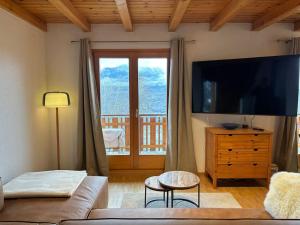 Grand Chalet Veysonnaz w/Spa في سيون: غرفة معيشة مع تلفزيون بشاشة مسطحة كبيرة
