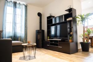 ein Wohnzimmer mit einem TV und einem schwarzen Entertainment-Center in der Unterkunft La Menorah in Le Creusot