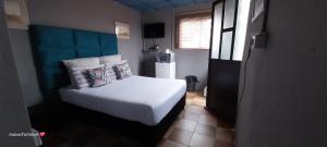 Rato Thato Guest House في ديربان: غرفة نوم بسرير ابيض وثلاجة
