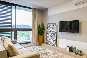 uma sala de estar com um sofá e uma grande janela em Apto incrível em Jurere Internacional - SRE505 em Florianópolis
