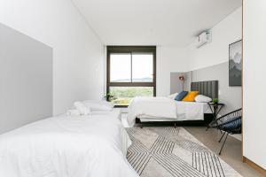 um quarto branco com 2 camas e uma janela em Apto incrível em Jurere Internacional - SRE505 em Florianópolis
