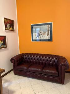 un sofá de cuero marrón en una habitación con una pared de color naranja en Francesca Apartment in Sassuolo - Affitti Brevi Italia, en Sassuolo
