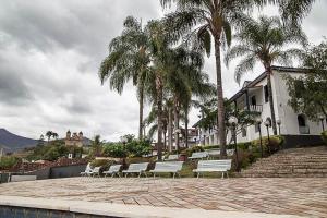 a row of white benches next to a building with palm trees at Hotel Providencia in Mariana