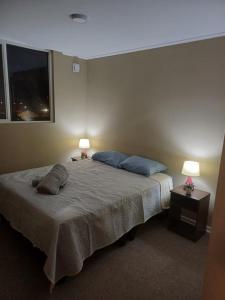 a bedroom with a bed with two lamps and a window at Departamento arriendo diario in Concepción
