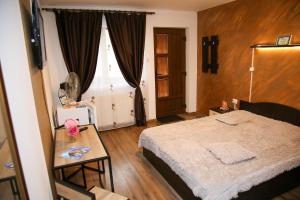 a bedroom with a bed and a table and a window at House Garden in Turda