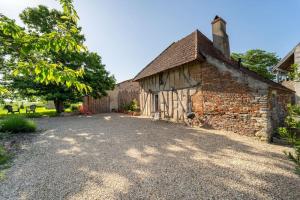 an old brick building with a gravel driveway at Le Petit Sondebois in Saint-Gervais-en-Vallière