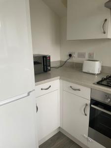 a white kitchen with a microwave and a toaster oven at Village House Cardiff - Close to A48 and M4 in Cardiff