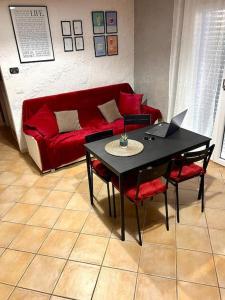 sala de estar con sofá rojo y mesa con ordenador portátil en Bed&Beach, en Fiumicino 2 fotos más