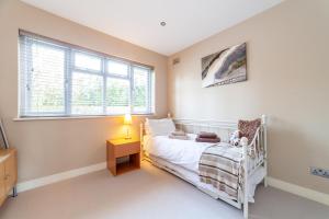 1 dormitorio con cama blanca y ventana en Garden Flat short walk to Kingston & Richmond Park, en Strawberry Hill
