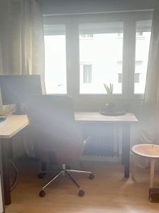 an office with a table and a chair and two windows at Apartamento Loft centro Santiago in Santiago de Compostela